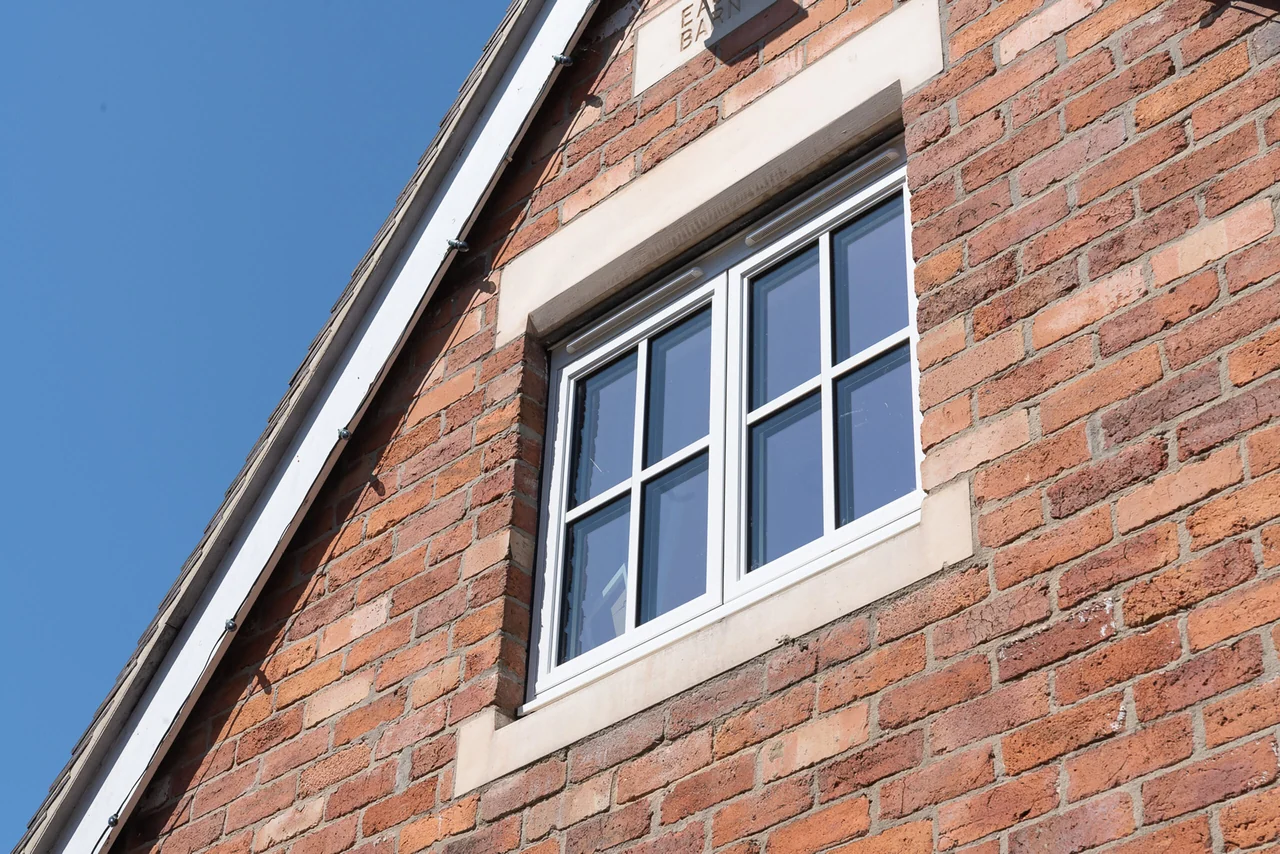 Real exterior photograph of a complete white Sheerline Classic casement window in a brick wall